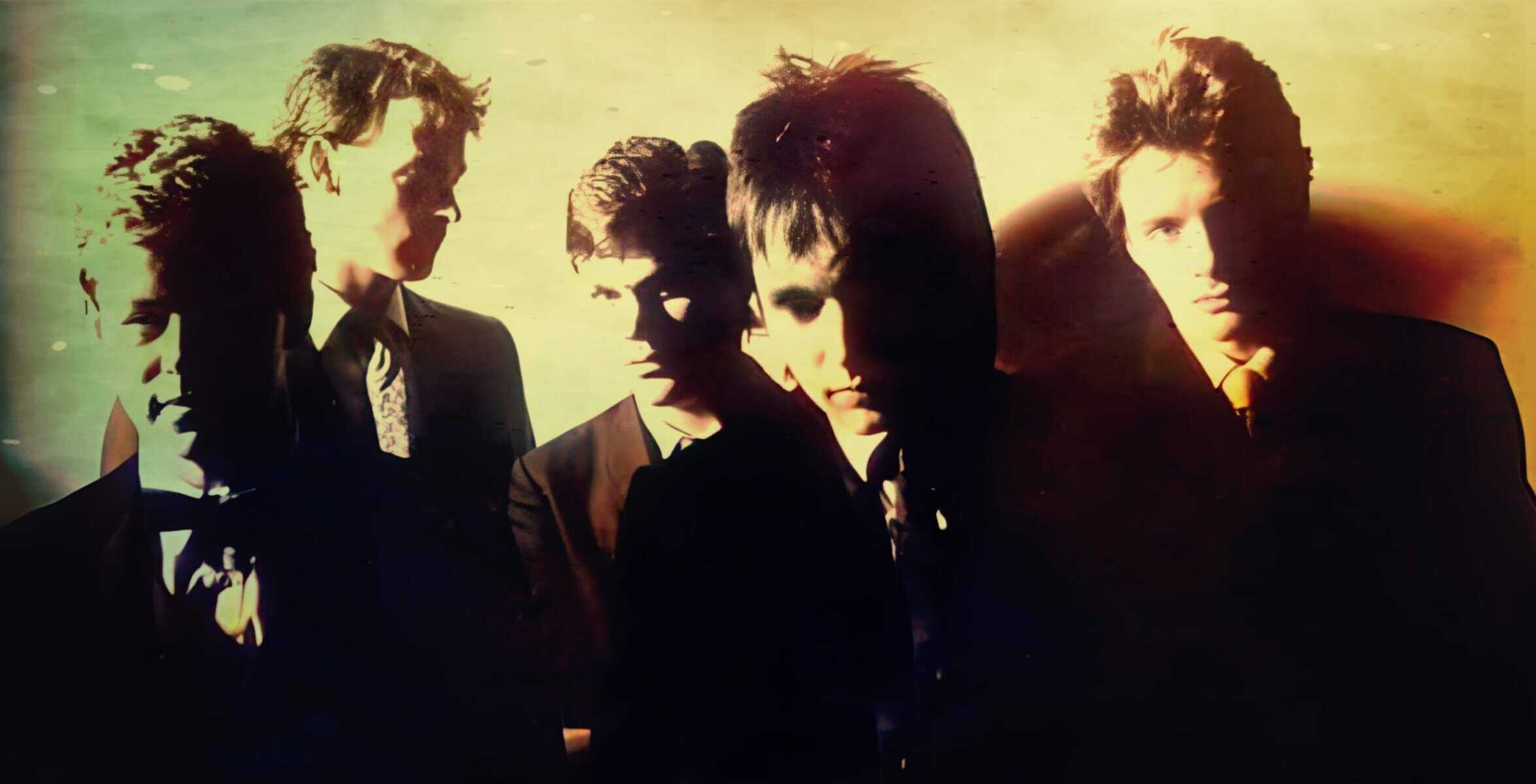 A vintage black and white photo of a 1980s band in suits, showcasing iconic style, perfect for music history and nostalgic 80s music themes.