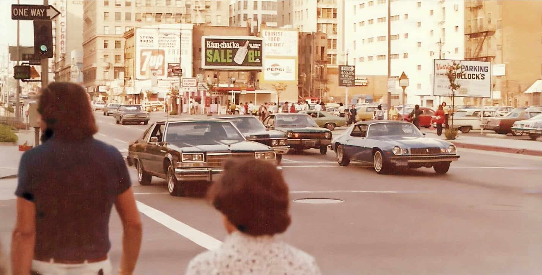 Vintage city street scene with classic cars and pedestrians, capturing the lively atmosphere of the 1980s urban environment in Los Angeles.