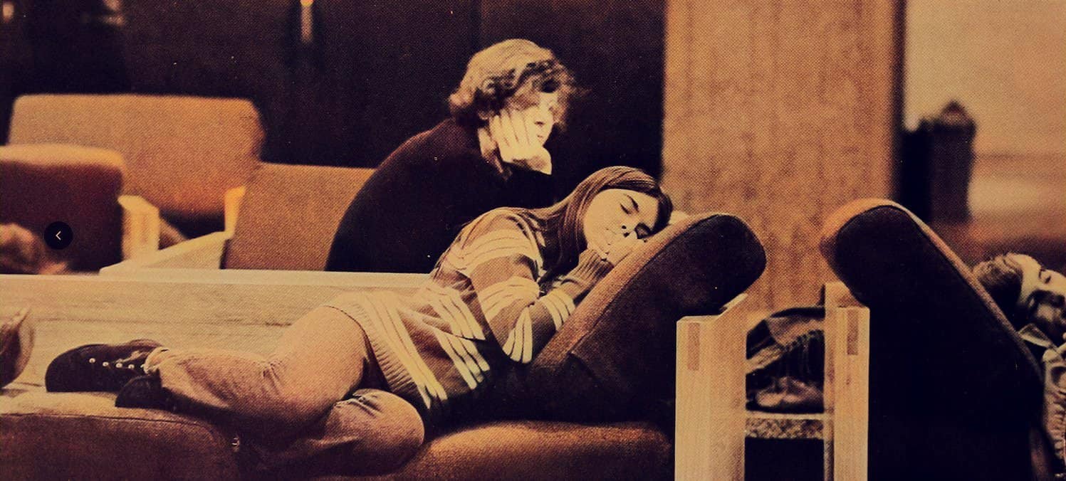 A young girl sleeps on a sofa while an older woman watches her thoughtfully, in a cozy indoor setting. It's a warm, nostalgic moment highlighting family, comfort, and relaxation. Perfect for nostalgic music and news archives.
