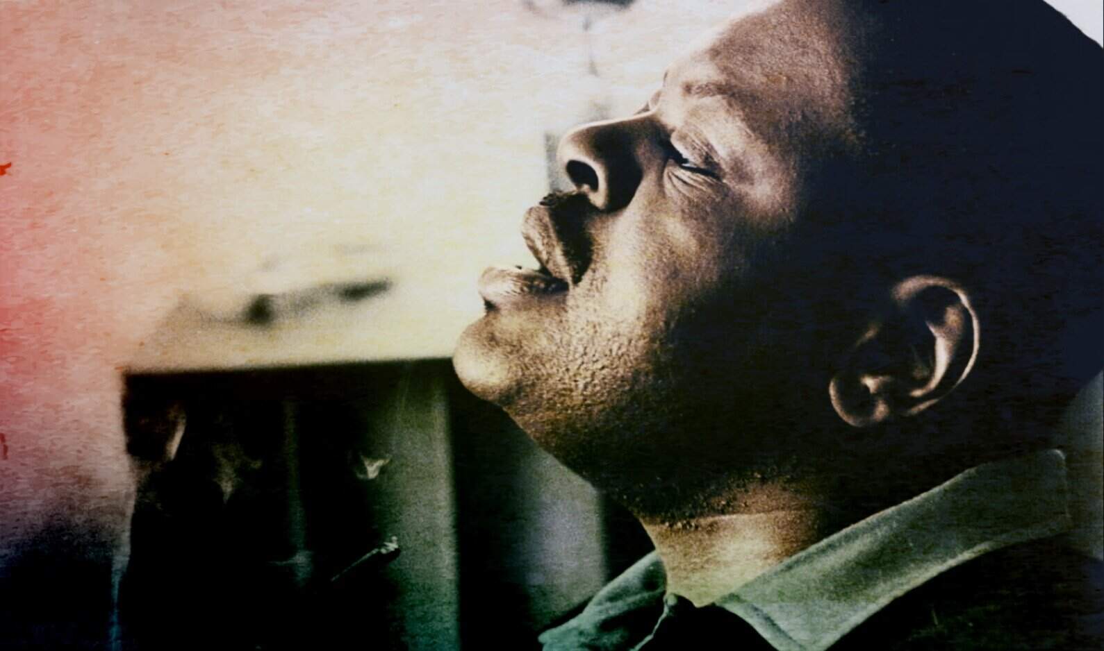 Close-up of a smiling African American man enjoying music inside a car, illustrating nostalgia and auditory enjoyment, aligned with past news, history, and music archives.