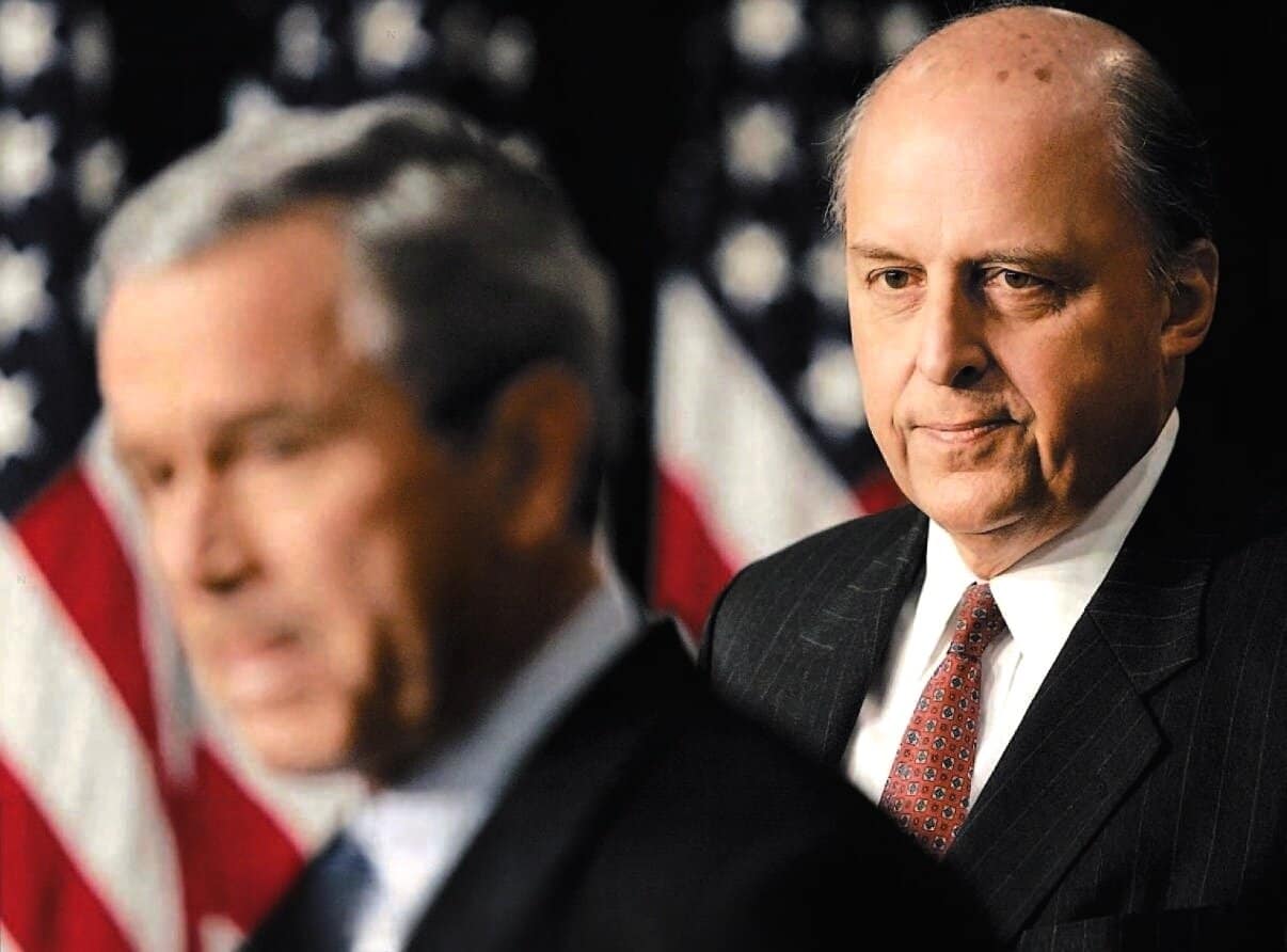 Political leaders at a press conference with American flags in the background.