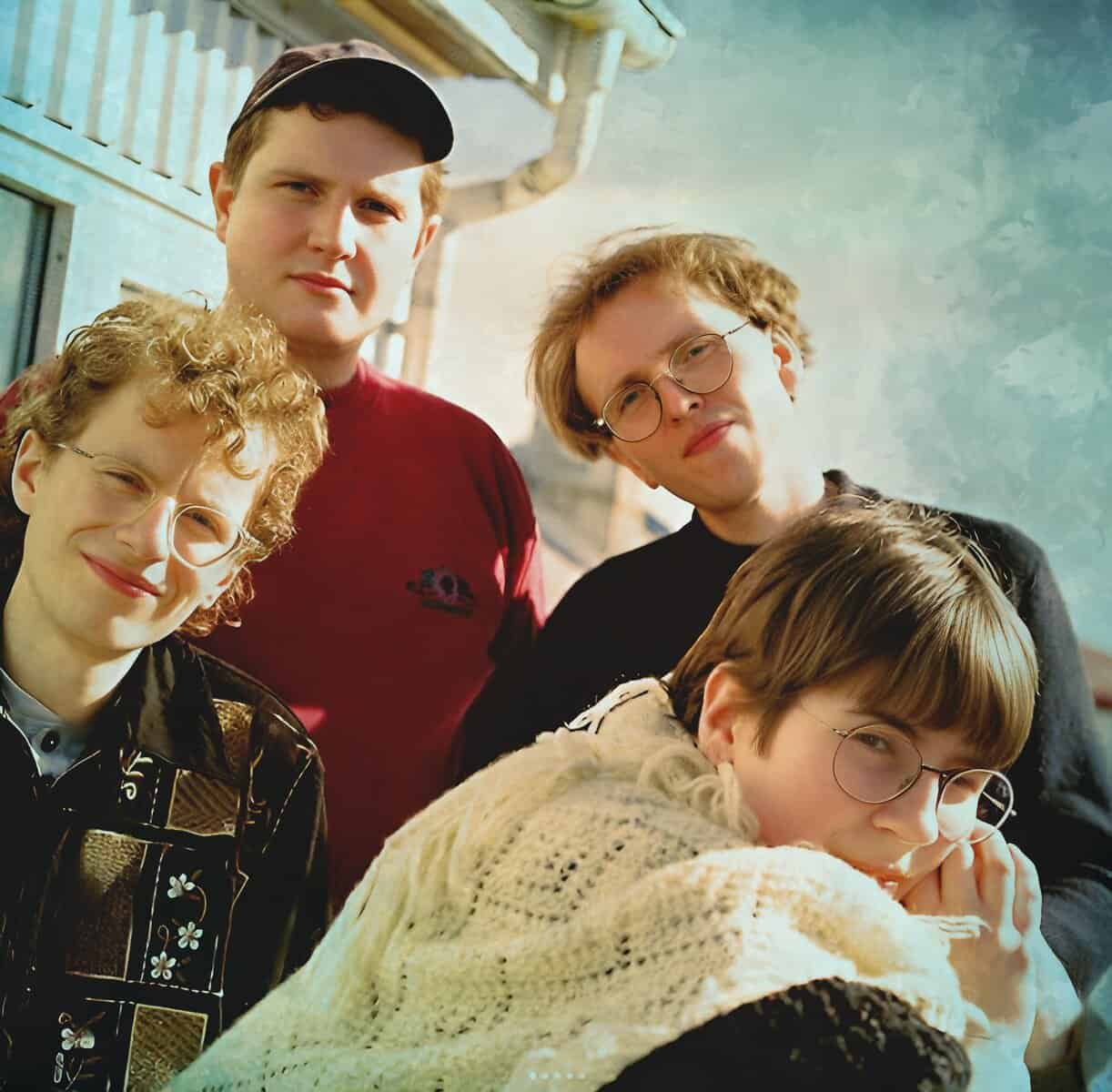 Vintage family photo featuring five young people with 90s fashion and glasses, capturing nostalgic moments.