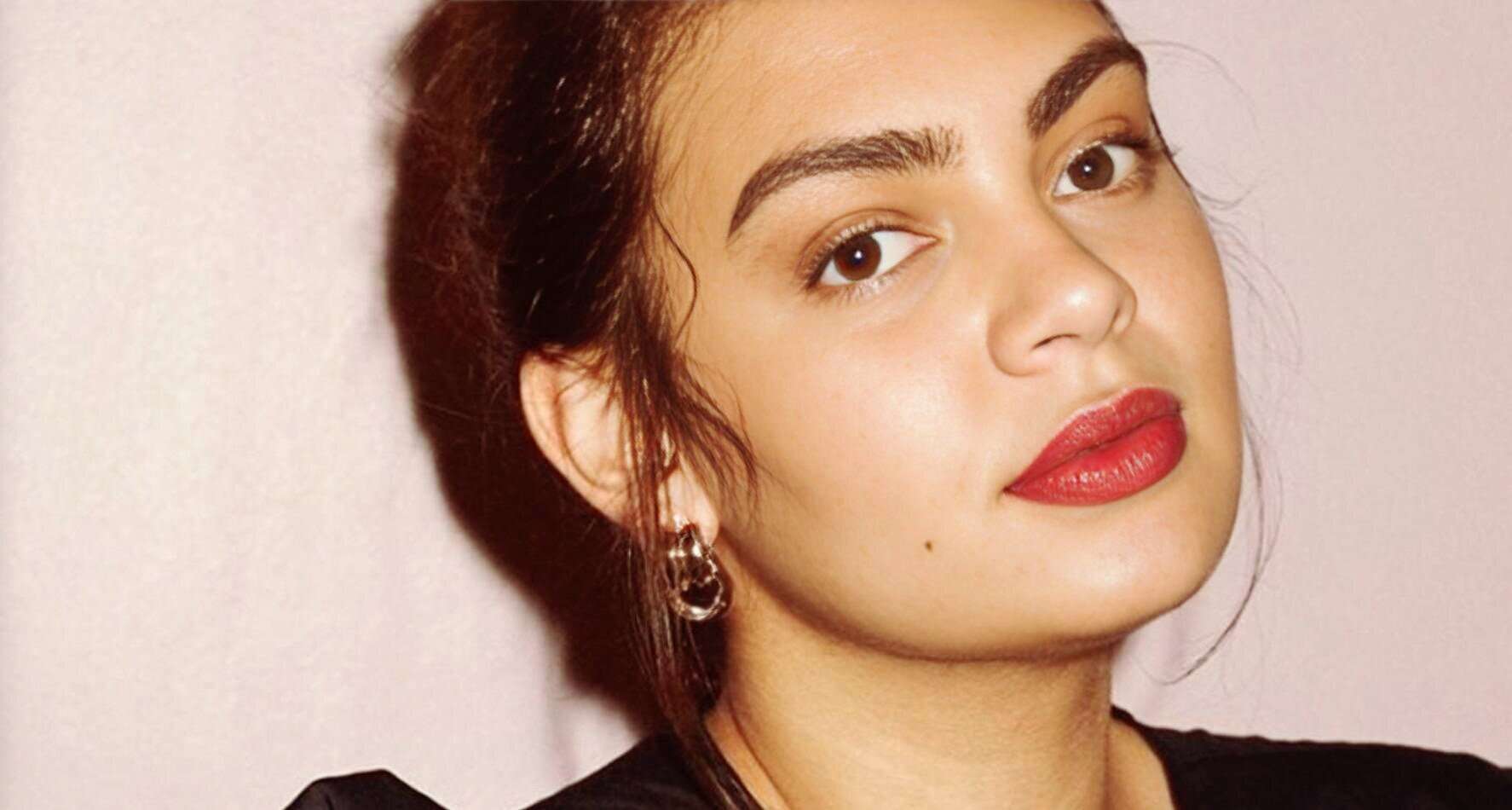 Beautiful woman with red lipstick and earrings, showcasing classic beauty and style, ideal for music and historical archives related to entertainment, fashion, and pop culture features.