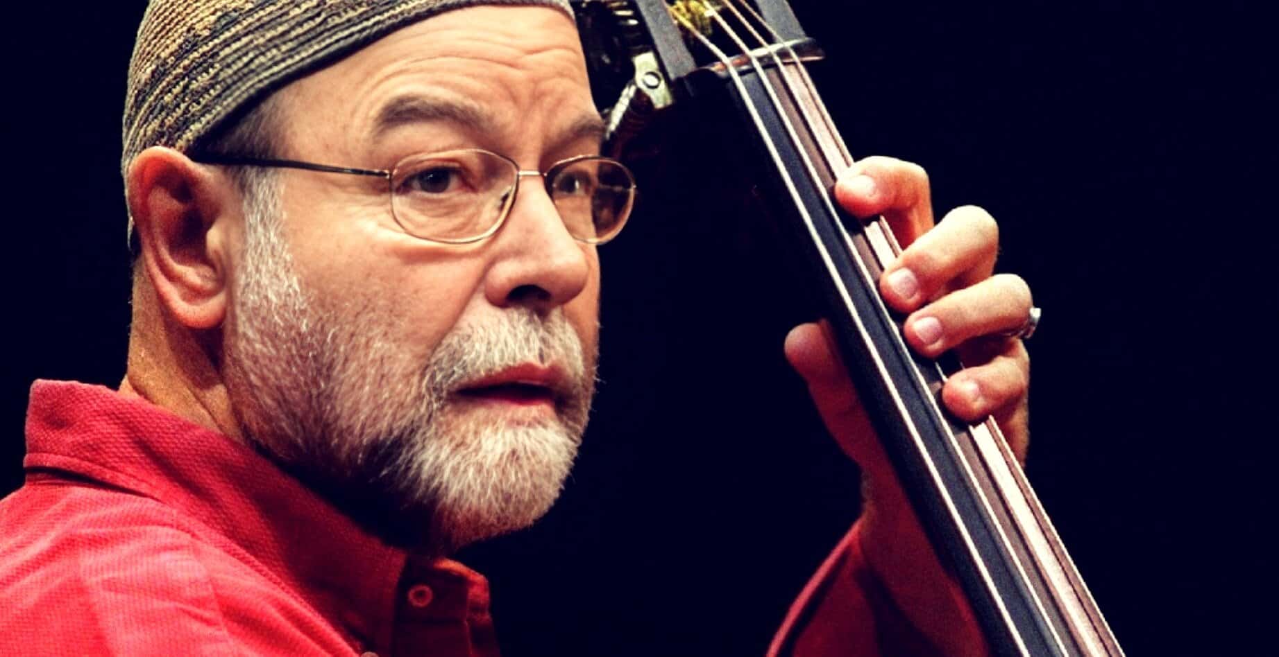 Close-up of an elderly man playing the upright bass, emphasizing jazz music, musical performance, and sound archive.