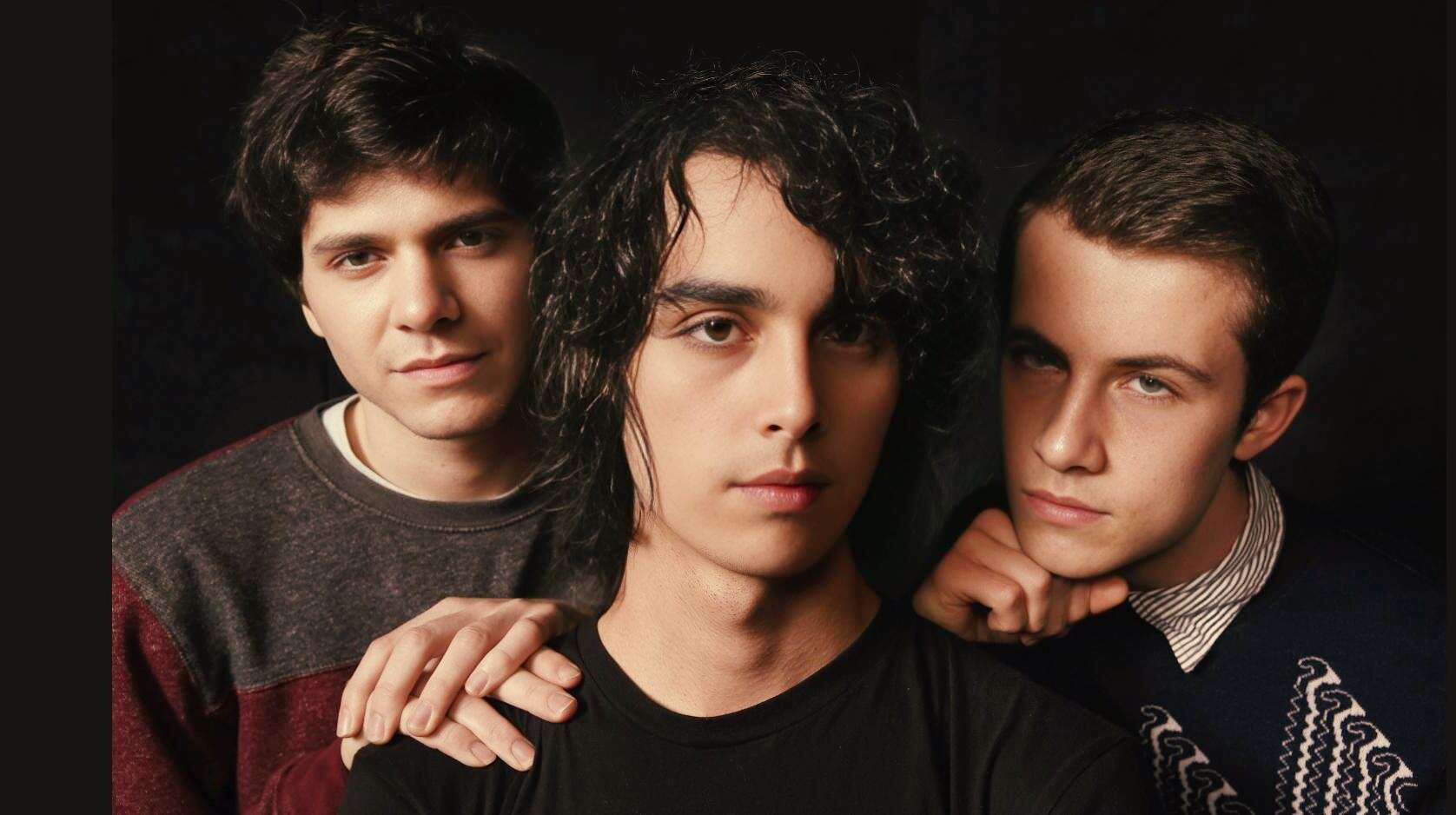 Vintage music band members portrait, close-up of young male musicians with serious expressions, dark background, highlighting music history and classic sound archive.
