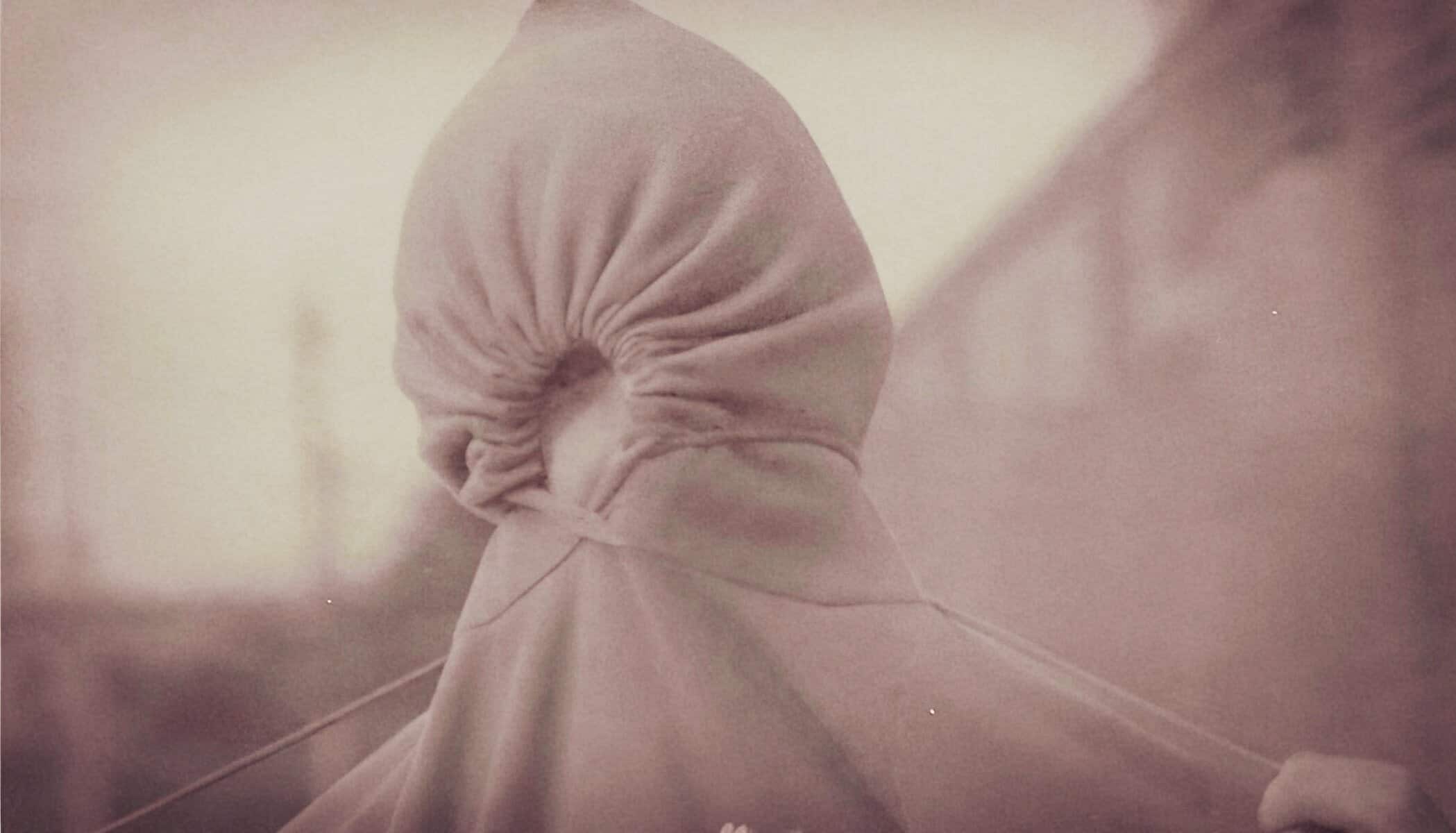 Hidden person wearing a hoodie, abstract figure, mystery theme, in a muted color palette, emphasizing anonymity and intrigue, suitable for news archives and historical audio content.