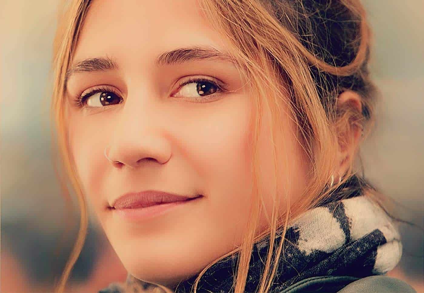 Close-up of a young woman with red hair and brown eyes, showcasing natural beauty and soft expression, ideal for media related to news, history, music, and sound archives.