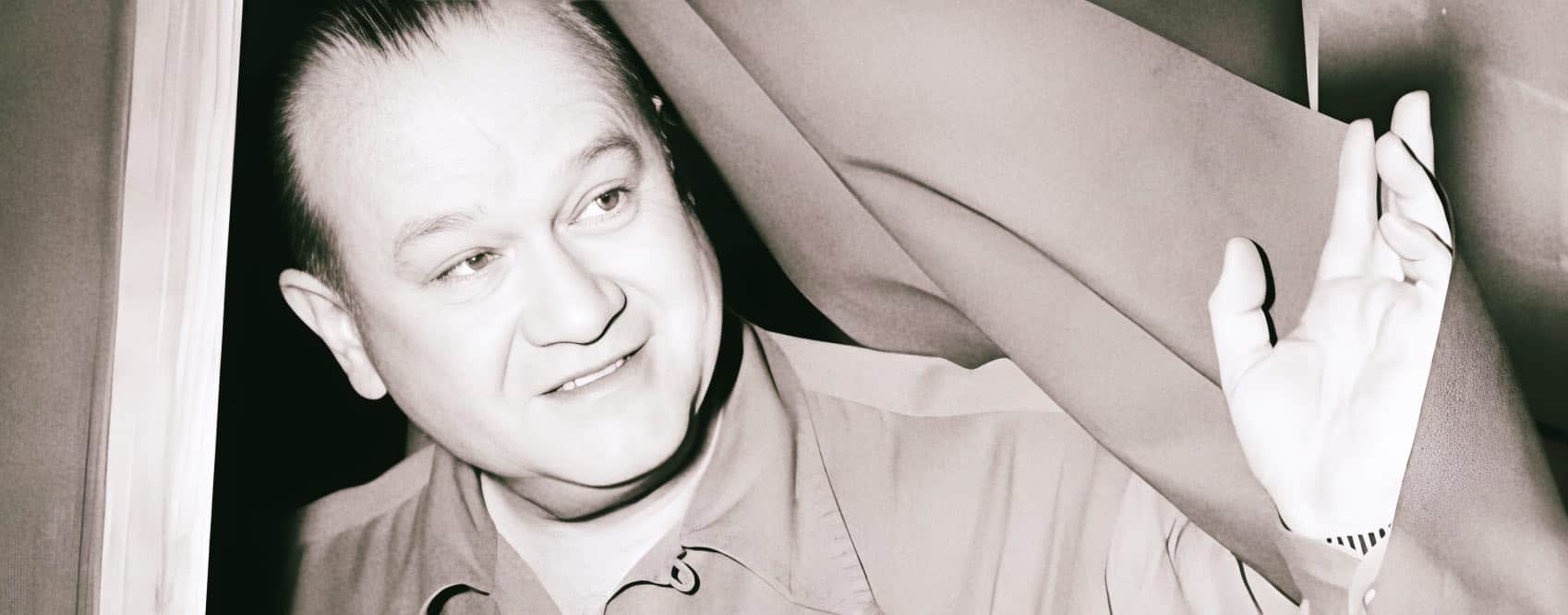 Vintage black and white photo of a man in a military uniform smiling and waving, representing historical news, music archives, and radio broadcasts.