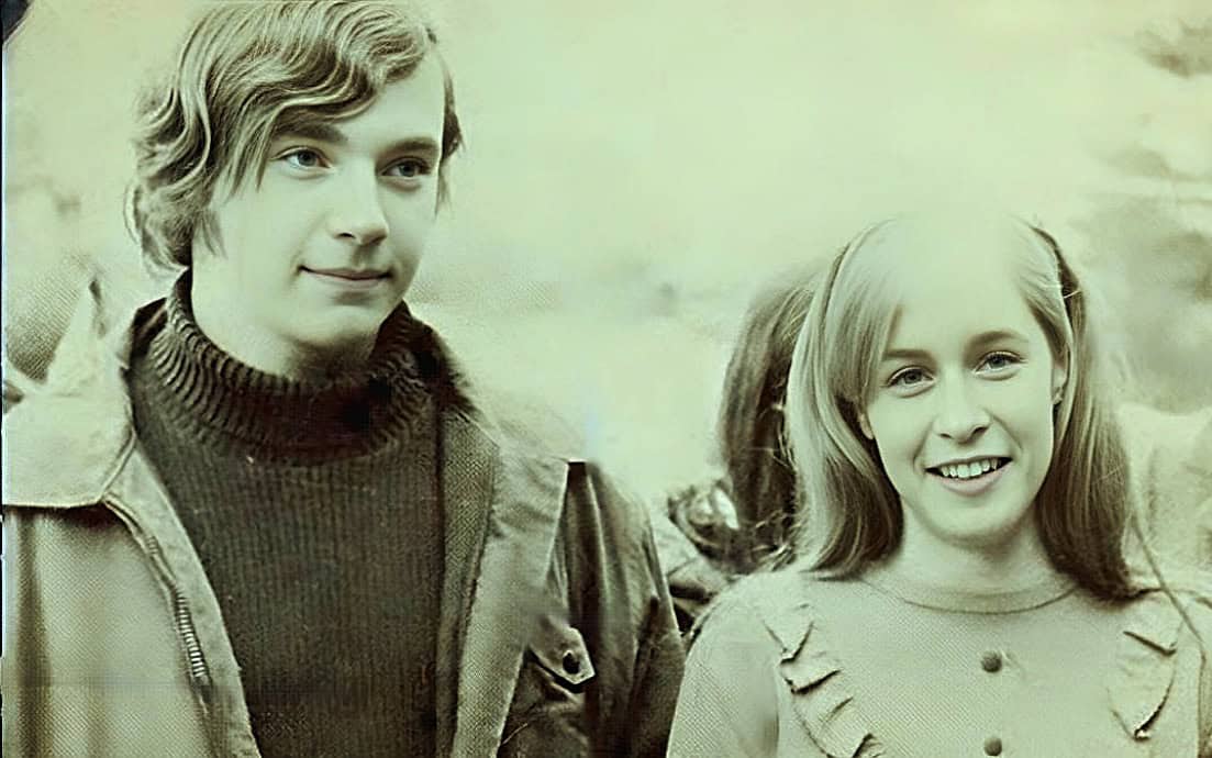 Youthful couple outdoor, 1960s fashion, nostalgic vintage photo, happy young man and woman, scenic background, historical candid portrait, classic American youth style.
