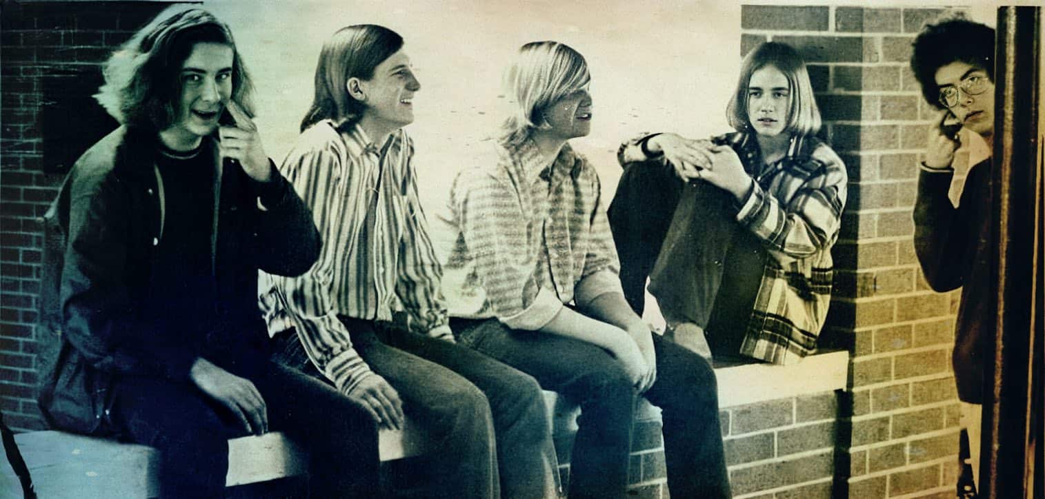 Teenage girls sitting and chatting outside, vintage black and white photo, nostalgic youth culture, school friends, candid moment, social interaction, early 1980s fashion, schoolyard scene, historical image of adolescent life.