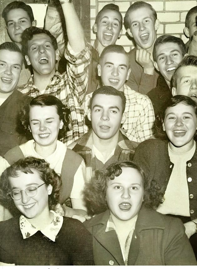 Teenagers laughing and having fun at a party or gathering, nostalgic black and white photo, vintage youth group photo, joyful social event, past daily archive, history of youthful friendships.