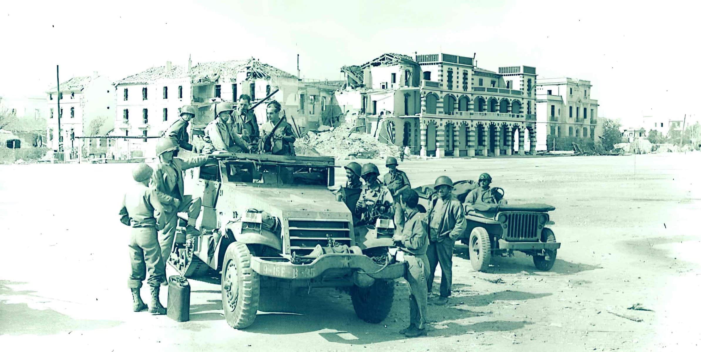 Military personnel and vehicles on patrol during wartime in front of damaged buildings, capturing a historical moment of conflict and resilience, with a focus on military history and war archives.