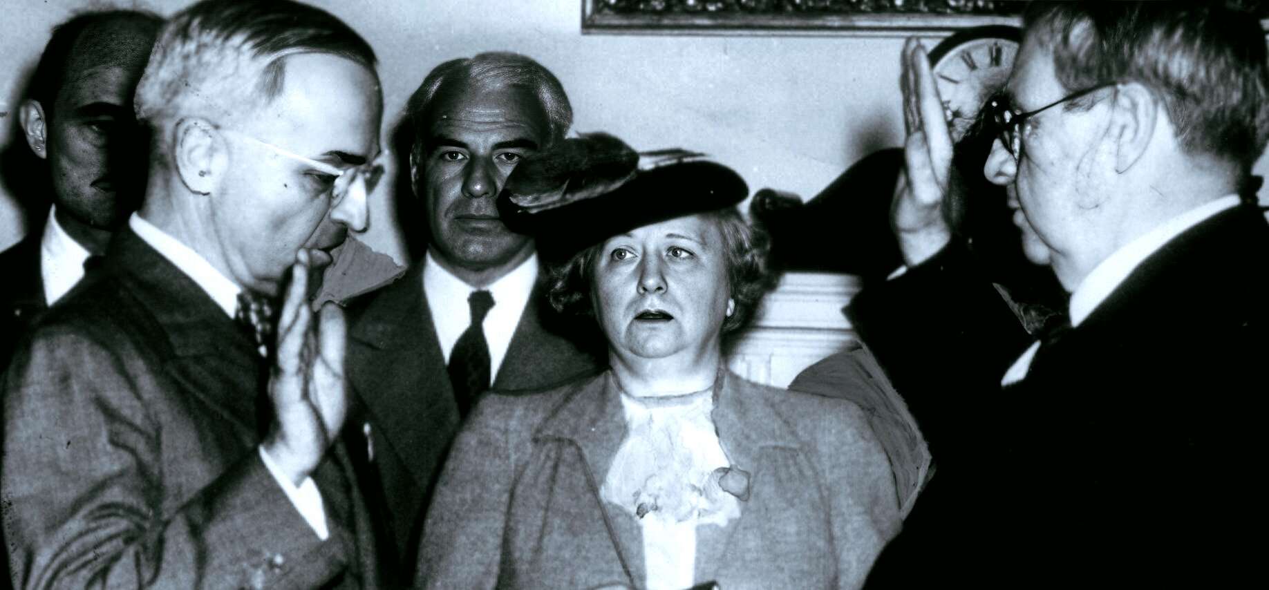 Historic black and white photo of Winston Churchill taking the oath of office as Prime Minister during WWII, surrounded by officials and military personnel, symbolizing key moments in history and political leadership.
