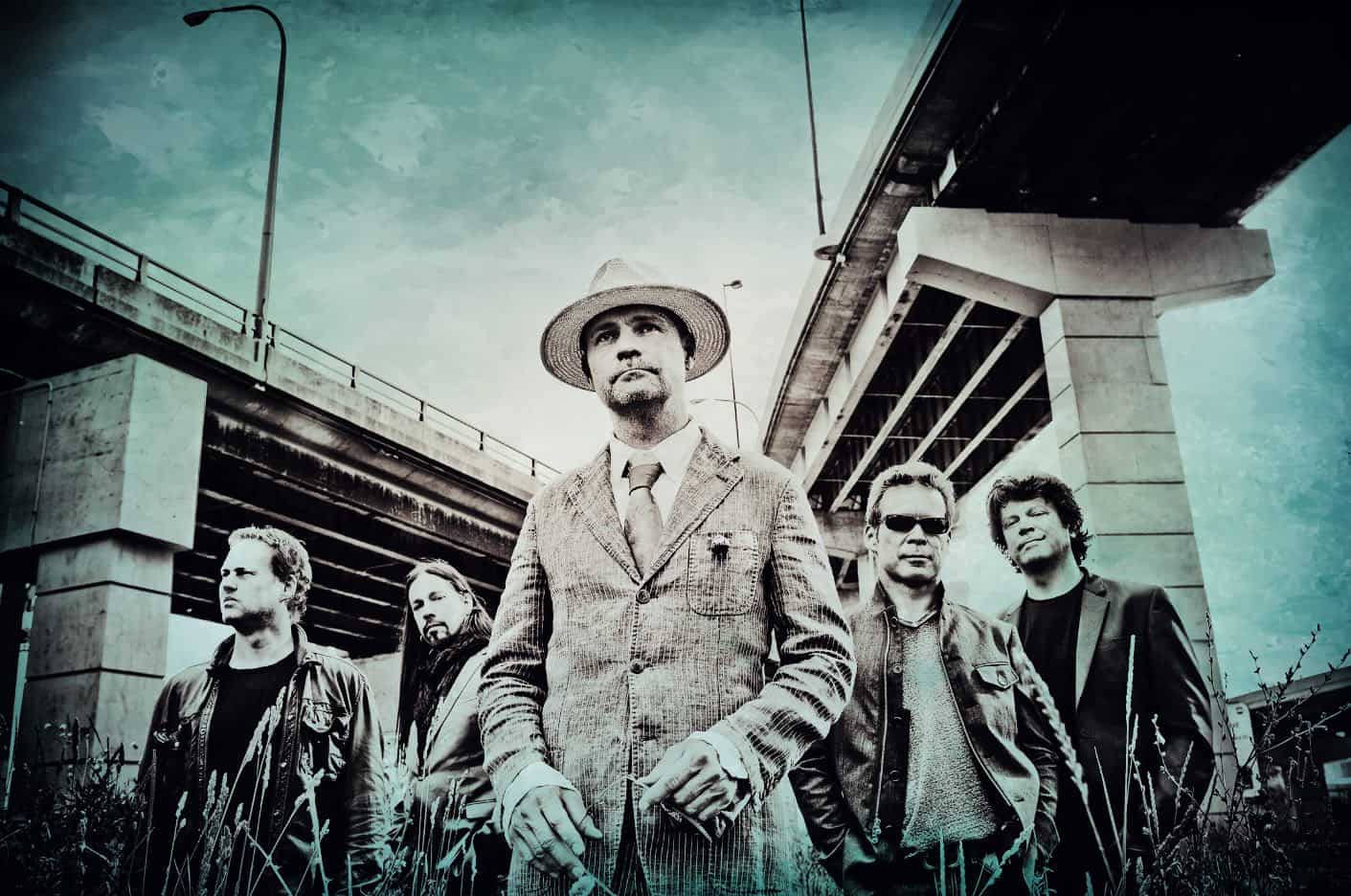 Vintage band portrait under an overpass, showcasing classic rock or alternative music style, emphasizing retro music archive, news, and history related to legendary bands.