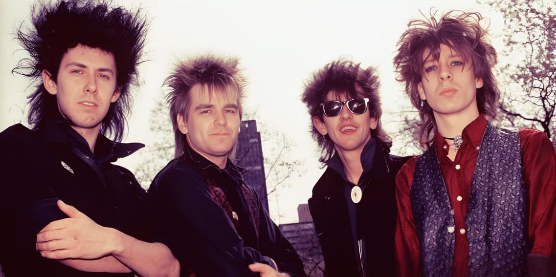 MTV rock band style, 1980s punk fashion, iconic musicians with wild hair, outdoor urban background, vibrant music scene, music history and news, retro music culture, vintage rock band photo, music archive, alternative music scene.