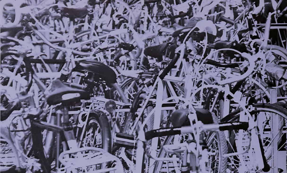 Bicycle pile, abandoned bikes, bicycle shortage, urban transportation, bike disposal, bike graveyard, bicycle recycling, bike junkyard, bike collection, bike history, past daily archive, historic bicycles, vintage bikes, bike storage, cycling history, bike loss, bike abandonment, bike storage facility, bike graveyard scene, bicycle surplus.