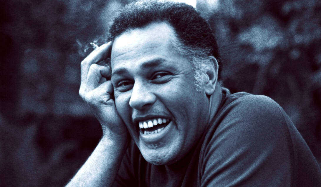 Black and white portrait of a smiling man laughing outdoors, relaxed and joyful mood.