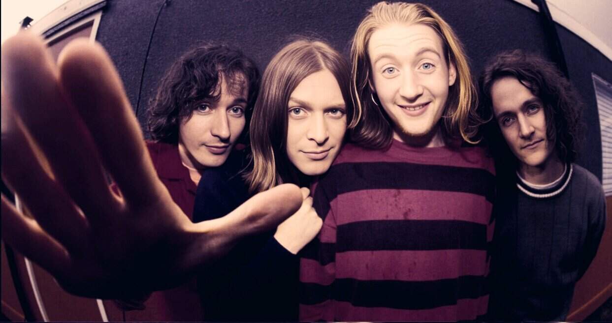 Vintage rock band photo featuring four young men with long hair, casual clothing, and confident expressions, representing iconic music history and timeless sound archives.