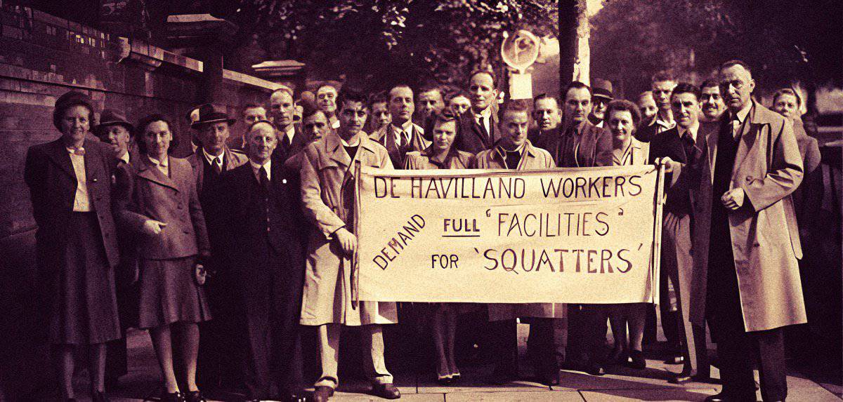 Workers protest sign demanding full facilities for squatters during historical labor movement. Vintage photo captures social activism, workers' rights, and community support in mid-20th century.