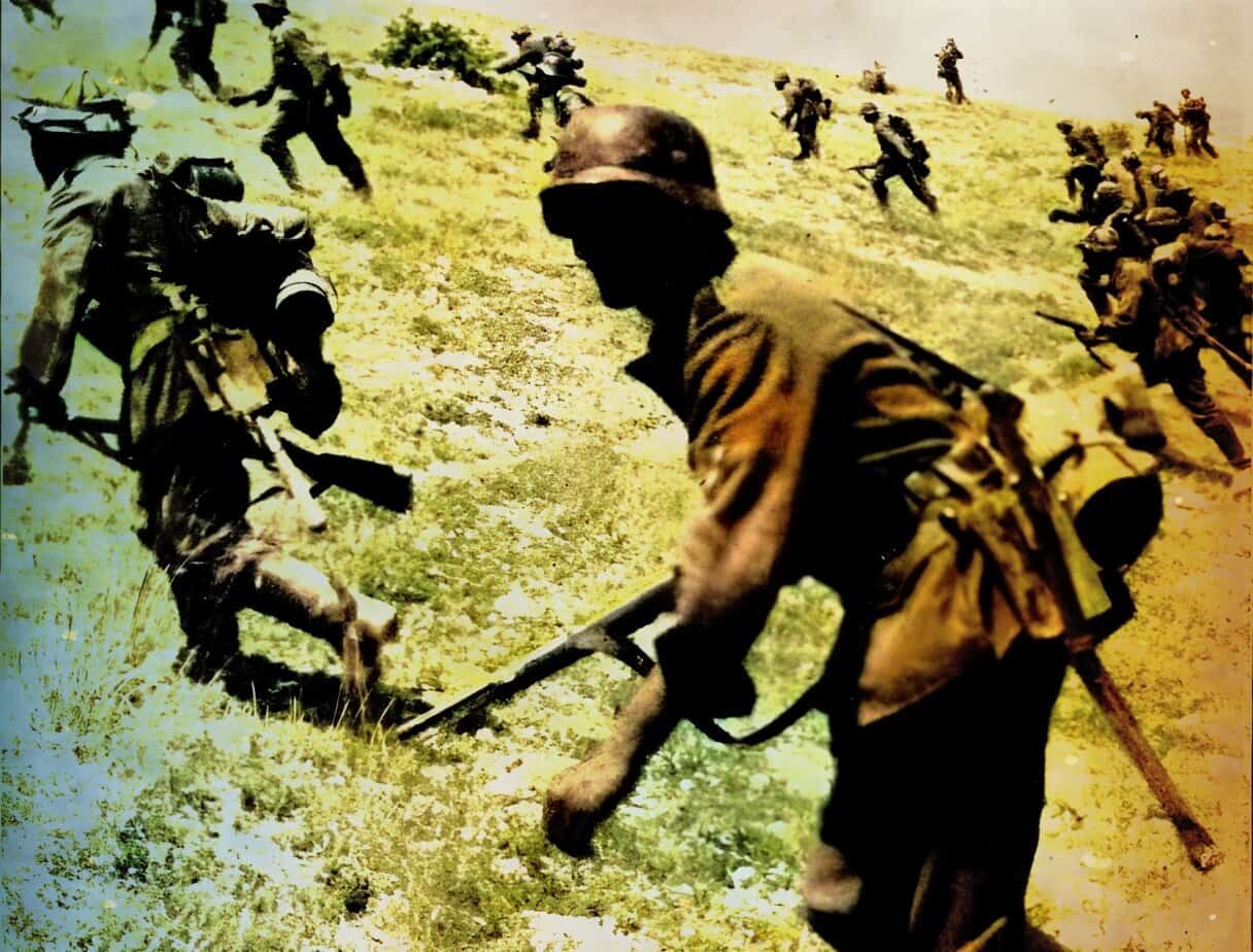 Soldiers during a military operation, armed and moving across a grassy hillside.