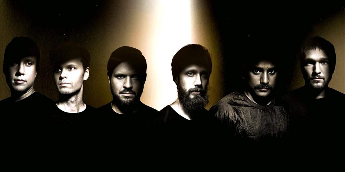 Dark-haired band members with serious expressions, musical group photo, modern music, band portrait, timeless style, music history imagery, reference to news archives, past daily news and music collection.