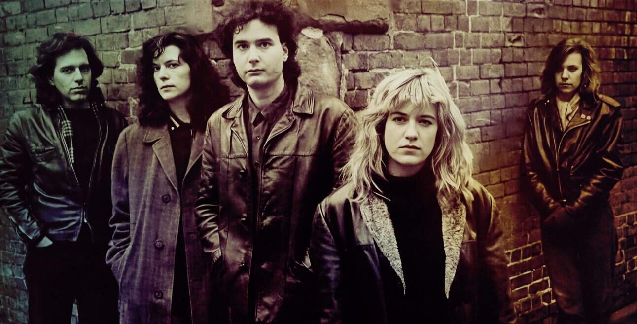 Dark Wave band standing against a brick wall, showcasing a vintage music scene with a moody and edgy aesthetic, perfect for nostalgic music archives.