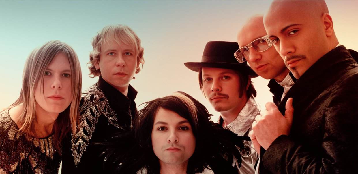 A vibrant music band with five members, showcasing diverse styles, performing under warm lighting, representing music history and archives from past daily news, history, and music collections.