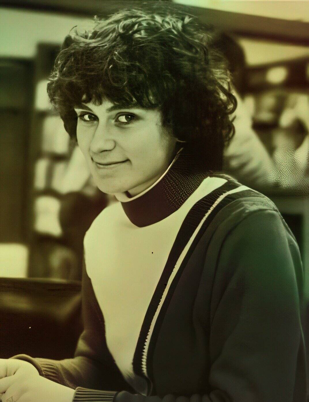 Young woman with curly hair smiling, vintage black and white portrait emphasizing nostalgia, classic style, and timeless appeal.