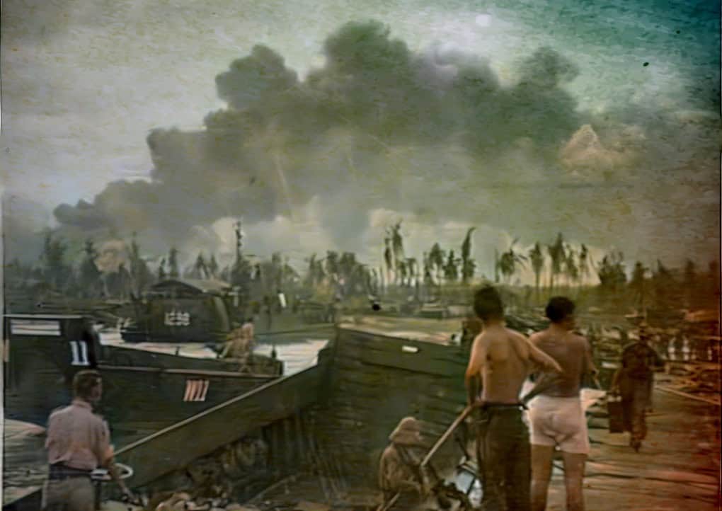 Smoke rising from war-damaged port with soldiers and civilians, historical military scene, wartime destruction, nostalgic photo of conflict, past daily news archive.