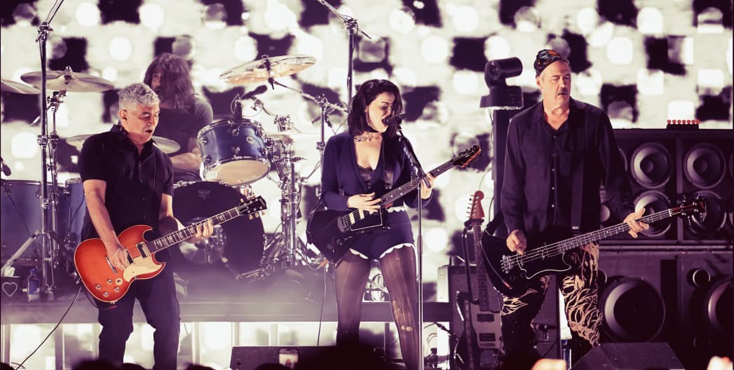 Rock band performing live music concert on stage with guitars and drums, vibrant concert lighting and sound equipment, representing music history and performance energy, related to music archives and historic performances.