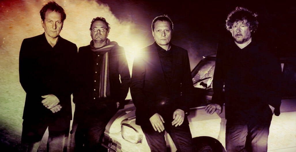 The Rolling Stones band members standing beside a car, promotional photo for classic rock music, rock band history, iconic musicians, music archive, vintage photography.