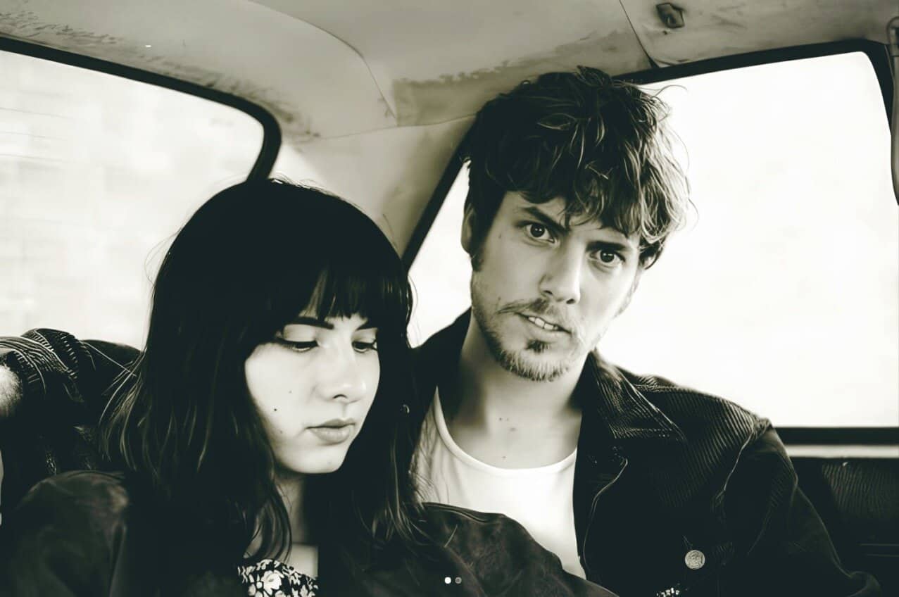 Vintage black and white photo of a young couple sitting inside a car, capturing a nostalgic moment, with a focus on music, history, and sound archive themes relevant to Past Daily.