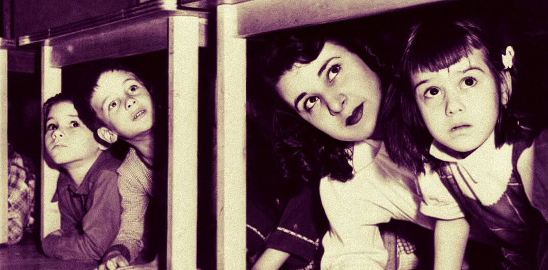 Laughing children peeking out from school desks in a classroom vintage black and white photo nostalgia for childhood education and school memories.