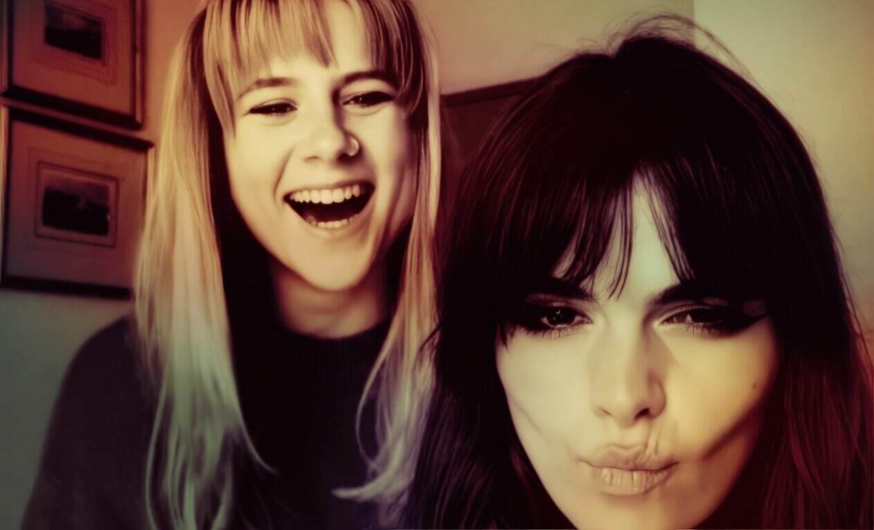 Young women smiling and posing for a photo, capturing lively and joyful expressions with vibrant hair colors; ideal for music, entertainment, and pop culture-themed content.