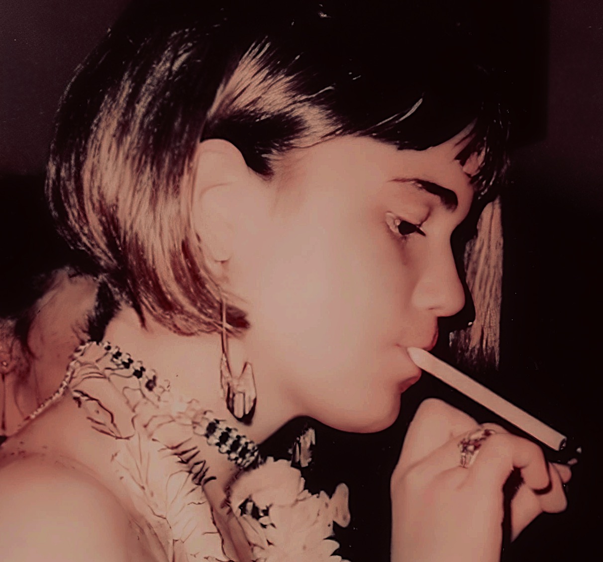 A vintage photograph of a woman with short hair smoking a cigarette, highlighting 90s fashion and style, perfect for nostalgic music and news history archives on Past Daily.