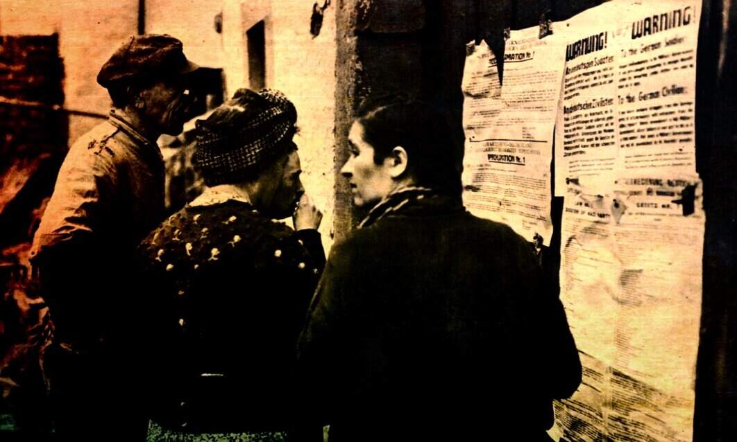 Historical black-and-white photo of three people reading notices posted on a wall, capturing glimpses of past social interactions and community communication.
