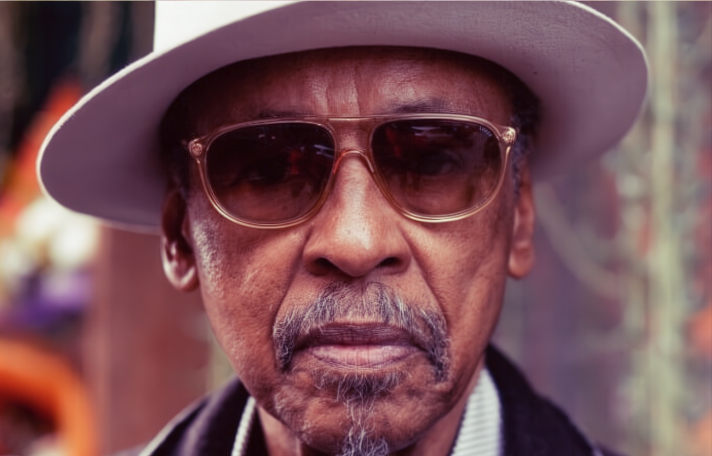 Vintage portrait of an elderly man wearing large sunglasses and a white hat, capturing a stylish and timeless look.