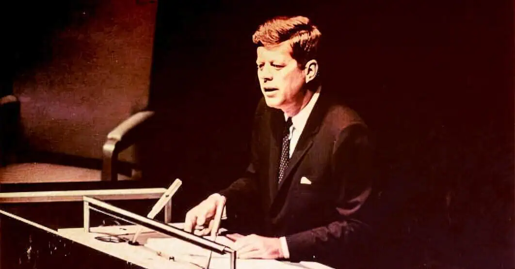 Vintage black-and-white image of a man in a suit passionately singing or speaking into a microphone while playing a piano, capturing the essence of classic music and broadcasting history.