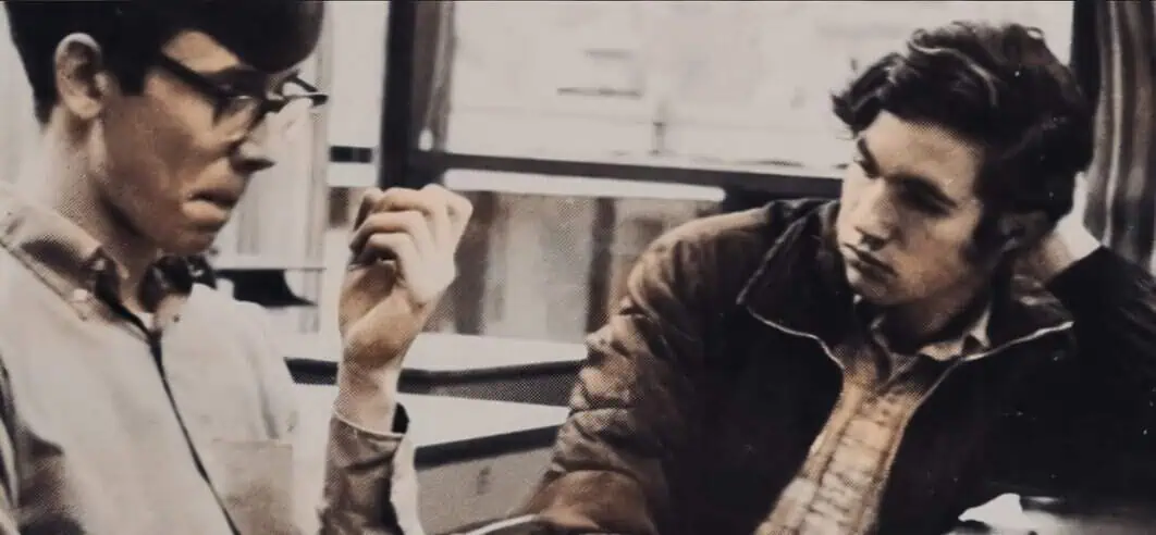 Unrecognizable young men engaged in conversation, capturing a nostalgic moment; black and white photo emphasizing the vintage vibe from the 1960s or 1970s.