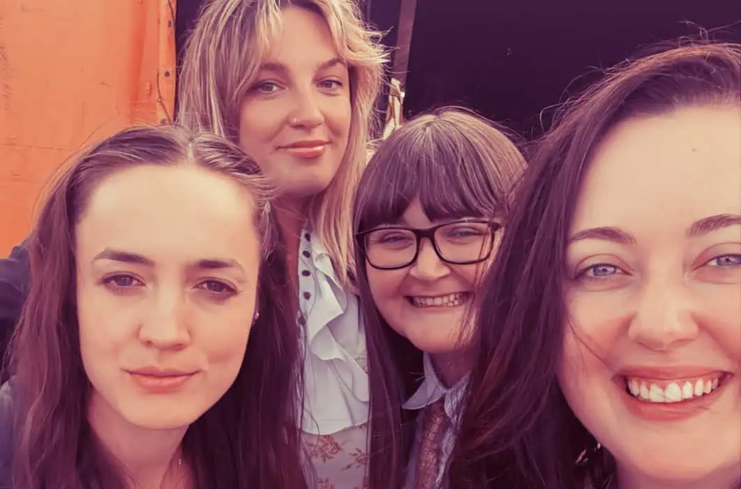 Girls smiling together, young women outdoor casual gathering, friends enjoying sunny day, cheerful group portrait, friendship and fun, vibrant social scene.