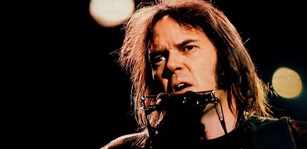 Rock singer David Bowie performing on stage during a concert, intense expression, colorful lights in the background.